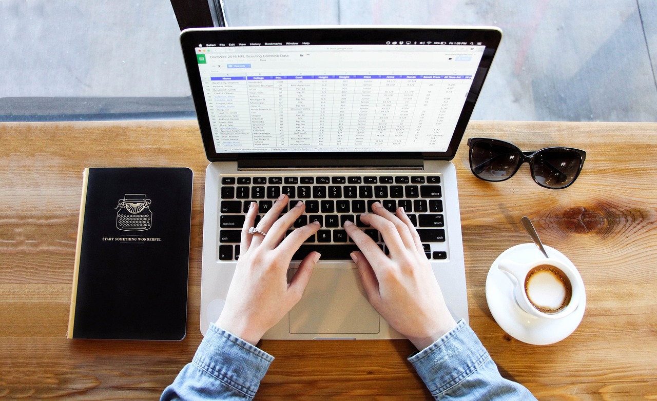 Pessoa digitando em notebook com café, montando o passo a passo do plano de negócios