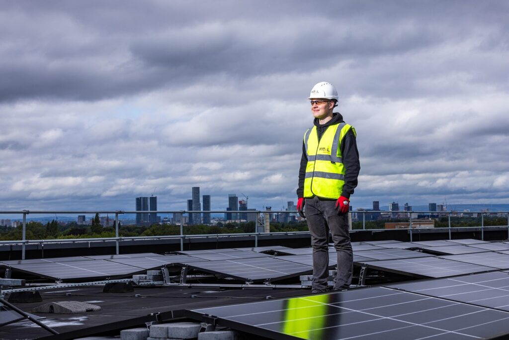 Trabalhador instalando painéis solares em telhado, exemplo de eficiência energética empresarial